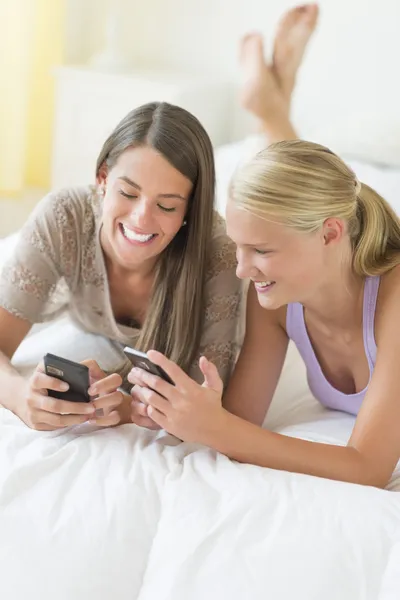 Fröhliche Freunde mit Smartphones im Bett — Stockfoto