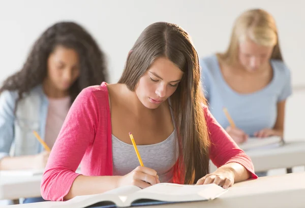 Teenage studenten schrijven in boek bij receptie — Stockfoto