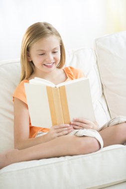 kız kanepede otururken kitap okuma