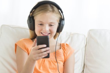 headp üzerinden müzik dinlerken cep telefonu tutan kız