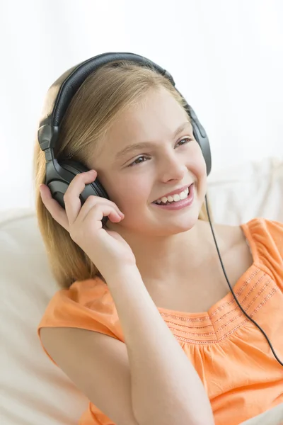 Menina olhando para longe enquanto escuta música através de fones de ouvido — Fotografia de Stock