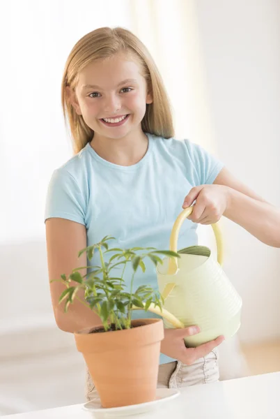 快乐的女孩浇水植物在家里 — 图库照片