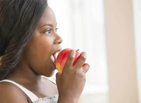 Menina comendo maçã fresca em casa — Fotografia de Stock