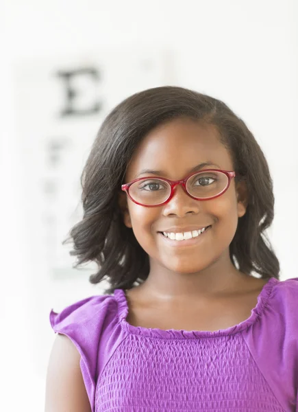 Chica sonriente usando gafas contra carta de ojos —  Fotos de Stock