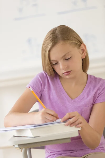 Mädchen schreibt Notizen in Buch am Schreibtisch — Stockfoto