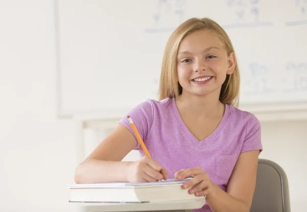 Schoolmeisje schrijven nota's in boek bij receptie — Stockfoto