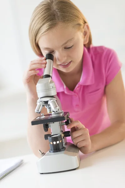 Chica mirando a través del microscopio en la clase de ciencias —  Fotos de Stock