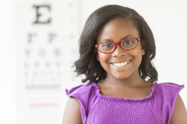 Dívka, která nosí brýle proti oko chart v klinice Royalty Free Stock Obrázky