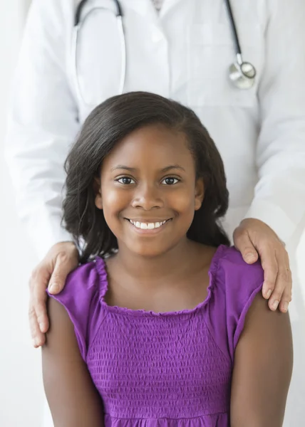 Leende flicka med läkare i bakgrunden på klinik — Stockfoto