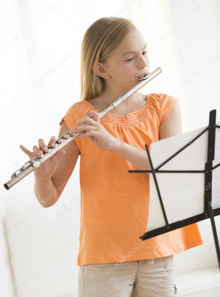 Girl Playing Flute At Home
