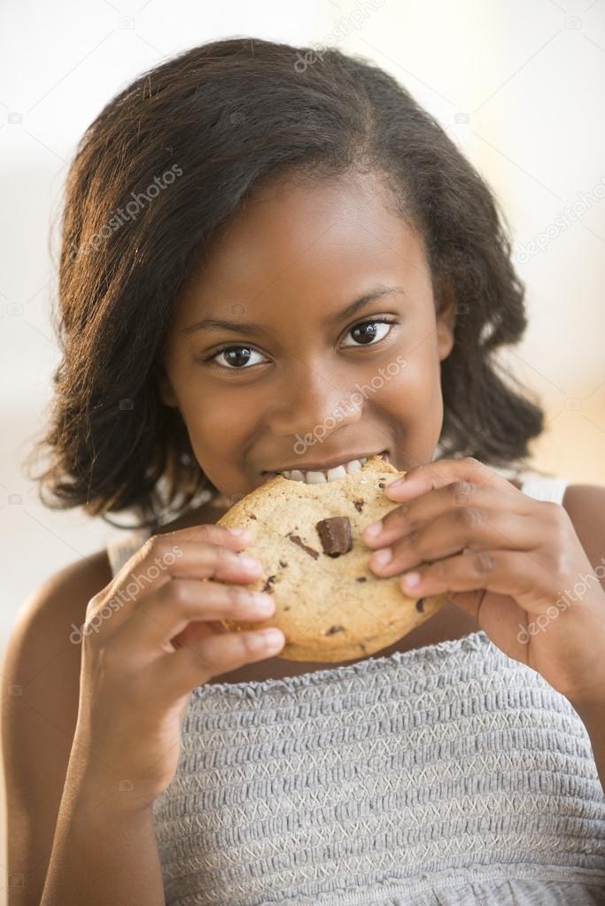 Girl Eating Chocolate Chip Cookie At Home