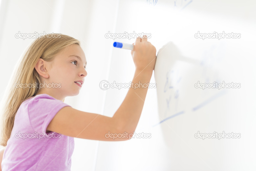 Schoolgirl Solving Math Problem On Whiteboard In Classroom