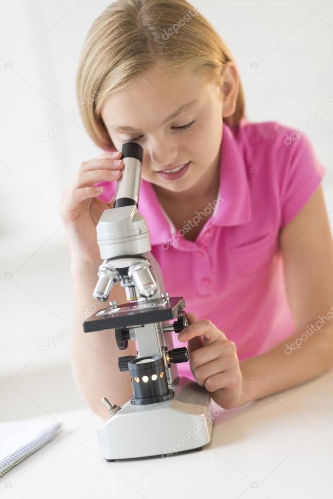 Girl Looking Through Microscope In Science Class