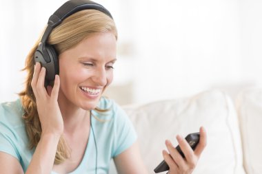 mutlu bir kadın kulaklık aracılığıyla müzik dinlemek