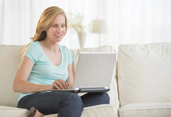 Kvinna som använder laptop på soffan i vardagsrummet — Stockfoto