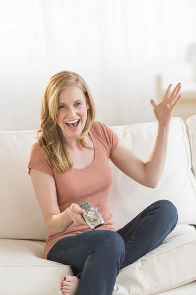 Kvinna med fjärrkontroll tittar tv soffan — Stockfoto