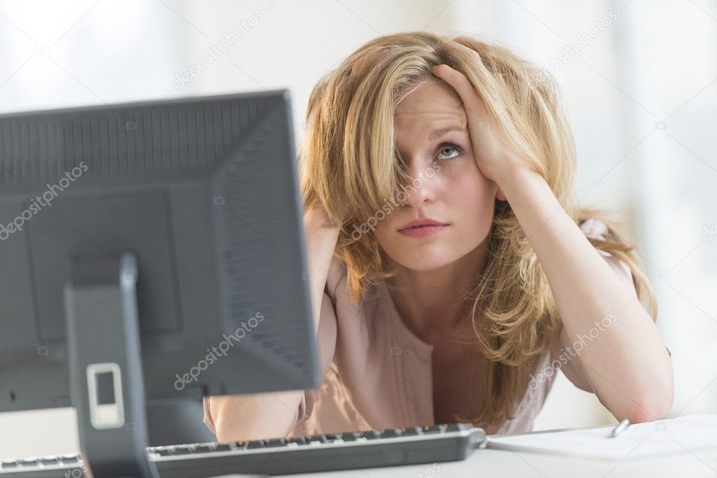 Frustrated Businesswoman With Hands In Hair At Office Desk