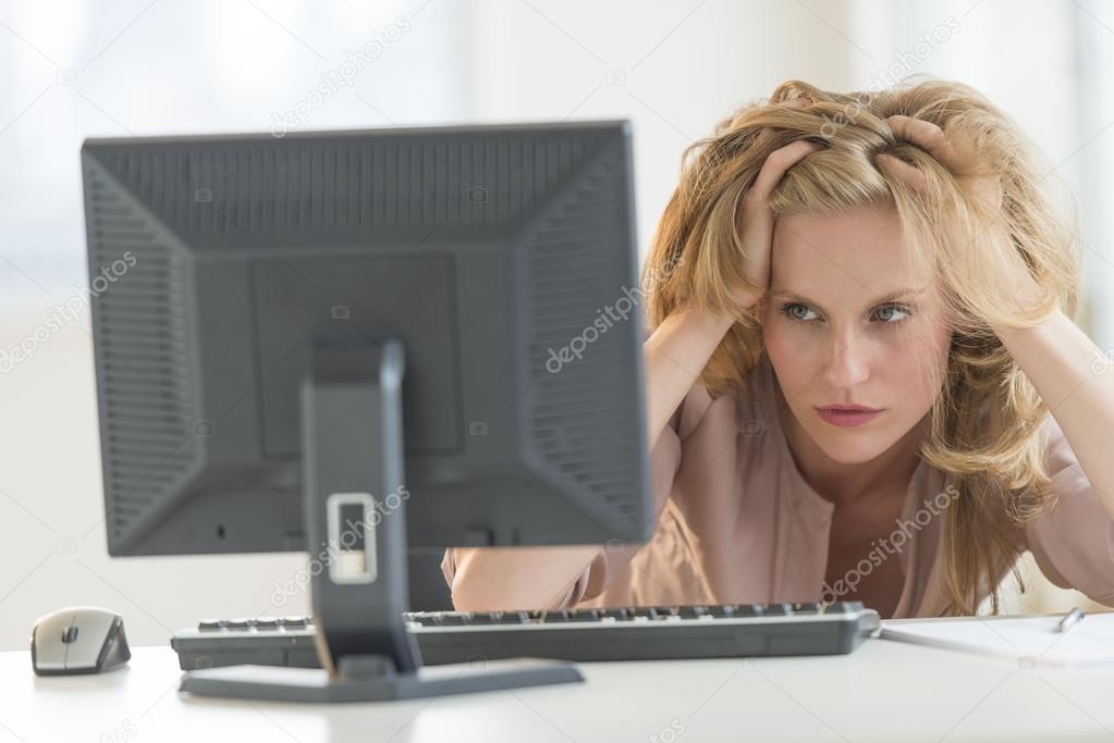 Frustrated Businesswoman Looking At Desktop PC In Office