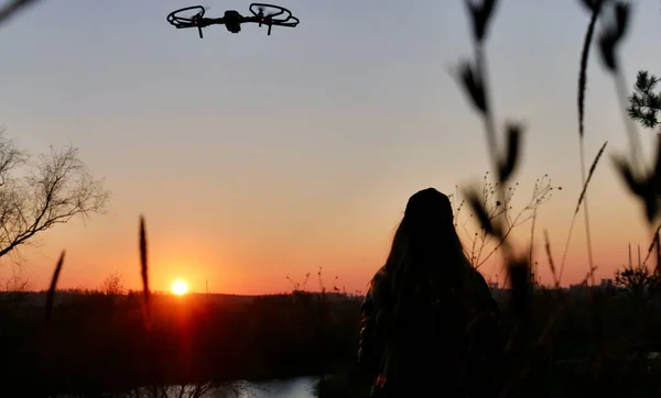 Mulher pilotando um drone ao pôr do sol — Fotografia de Stock