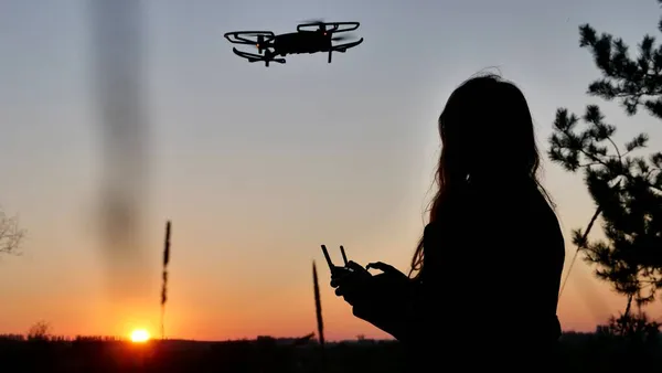 Mujer pilotando un dron al atardecer Imágenes de stock libres de derechos