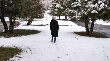 Genç bir kadın kış ormanında yürüyor.