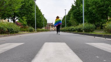 Woman lesbian with LGBT flag on sky road