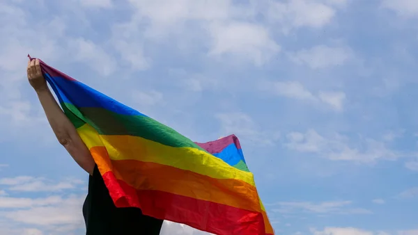 天空背景下高举LGBT旗的变性人 — 图库照片