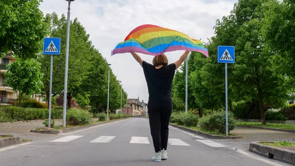 Mulher lésbica com bandeira LGBT na estrada do céu Imagens Royalty-Free