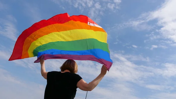 HBTQ-person med hbt-flagga på himlen bakgrund — Stockfoto