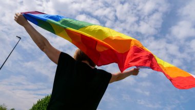 LGBT gururu, gökkuşağı barış bayrağı mavi gökyüzüne karşı güneşli bir günde ve Biseksüellik Günü 'nü ya da Ulusal Açılış Günü' nü kutlayın
