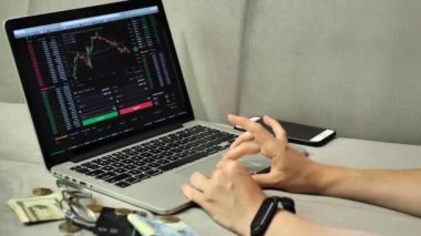 Laptop and phone to buy bitcoin on the Binance crypto exchange during the market crash. Trading, spot, staking. Workspace freelance, woman hands on keyboard 
