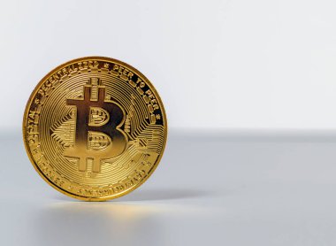 Gri arkaplanda yansıması olan altın renkli bitcoin para.