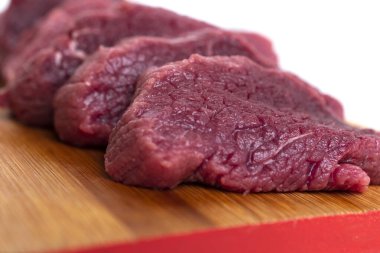 Tahta kesme tahtasında dilimlenmiş çiğ kırmızı et.