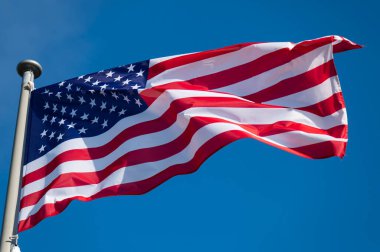 Rüzgarda dalgalanan Amerikan bayrağı açık mavi gökyüzüne karşı.