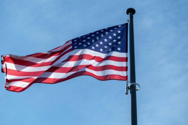 Rüzgarda dalgalanan Amerikan bayrağı açık mavi gökyüzüne karşı.