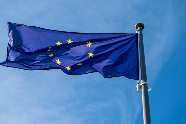 European union flag waving in the wind against clear blue sky.