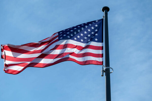 American flag waving in the wind against clear blue sky.