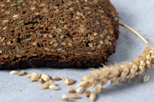 Doğal keten arkaplanda tohumlu, kurutulmuş buğdaylı kara ekmek..