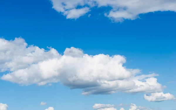 Sunny fluffy white cumulus clouds at summer sky.
