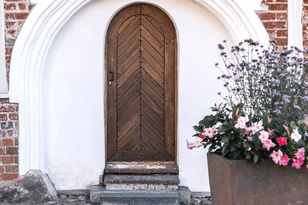 Entrance of ancient wooden doors and flower near it.