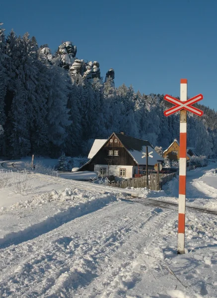 Schneeglatter Bahnübergang unter den Felsen von adršpach mit einem Haus — Stockfoto