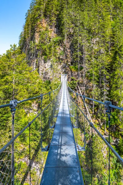 Simple suspension footbridge over mountain valley of Riesach waterfall. Schladminger Alps, Austria