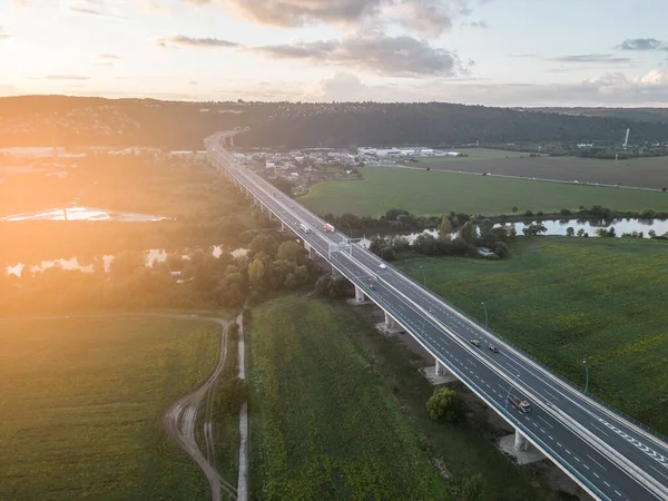 Cars and trucks traffic on highway bridge. Sunset flare on sunny summer evening. Lahovicky Bridge in Prague, Czech Republic. Aerial view from drone.