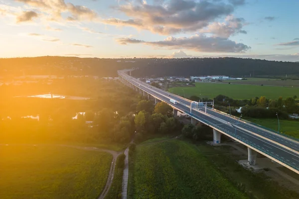 Cars and trucks traffic on highway bridge. Sunset flare on sunny summer evening. Lahovicky Bridge in Prague, Czech Republic. Aerial view from drone.