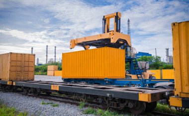 Forklift kamyonu bir tren istasyonunda kargo konteynırlarını kaldırıyor, dağıtım terminali mallarının yüklenmesini bekleyen demiryolu ithalat ve ihracat lojistik taşımacılık konsepti..