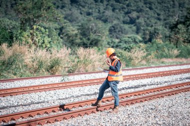Mühendis teftiş altında ve inşaat sürecinde demiryolu şalterini kontrol ediyor ve tren istasyonundaki işi kontrol ediyor. İş yerinde güvenlik üniforması ve güvenlik kaskı takan bir mühendis..