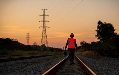 Mühendis teftiş altında ve inşaat sürecinde demiryolu şalterini kontrol ediyor ve tren istasyonundaki işi kontrol ediyor. İş yerinde güvenlik üniforması ve güvenlik kaskı takan bir mühendis..