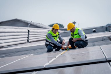 Çatıda yürüyen mühendisler ekipman kutusu ve telsiz iletişimiyle güneş hücresi panelini inceler ve kontrol ederler. Güneş pili akıllı ızgara ekolojik enerji alternatif enerji güneş ışığı enerji fabrikası konseptidir..