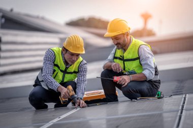 Çatıda yürüyen mühendisler ekipman kutusu ve telsiz iletişimiyle güneş hücresi panelini inceler ve kontrol ederler. Güneş pili akıllı ızgara ekolojik enerji alternatif enerji güneş ışığı enerji fabrikası konseptidir..