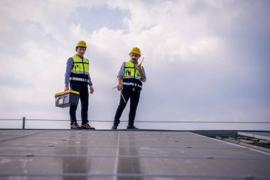 Çatıda yürüyen mühendisler ekipman kutusu ve telsiz iletişimiyle güneş hücresi panelini inceler ve kontrol ederler. Güneş pili akıllı ızgara ekolojik enerji alternatif enerji güneş ışığı enerji fabrikası konseptidir..